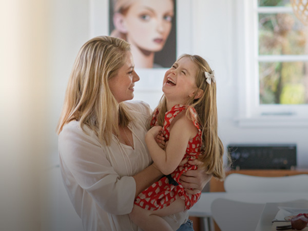 Woman holding daughter in her arms who is laughing