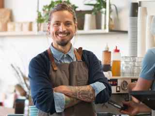 Smiling male barista with arms folded 